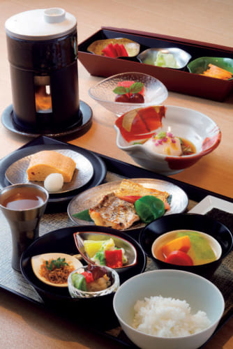 『KIZAHASHI/階きざはし』の和朝食の一例、3800円。手前の盆は目覚めのお出汁、出汁巻き玉子、太刀魚の炭火焼きとたたみいわし、野菜の炊き合わせなど。中央は銀杏胡麻豆腐、奥は香の物。白飯は目の前で炊く。