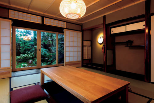 新旧の建具が調和する8畳の和室。掘りごたつ式のカリモク家具の桜材の座卓が置かれる。最大8名で利用できるので3世代旅行にも向く。